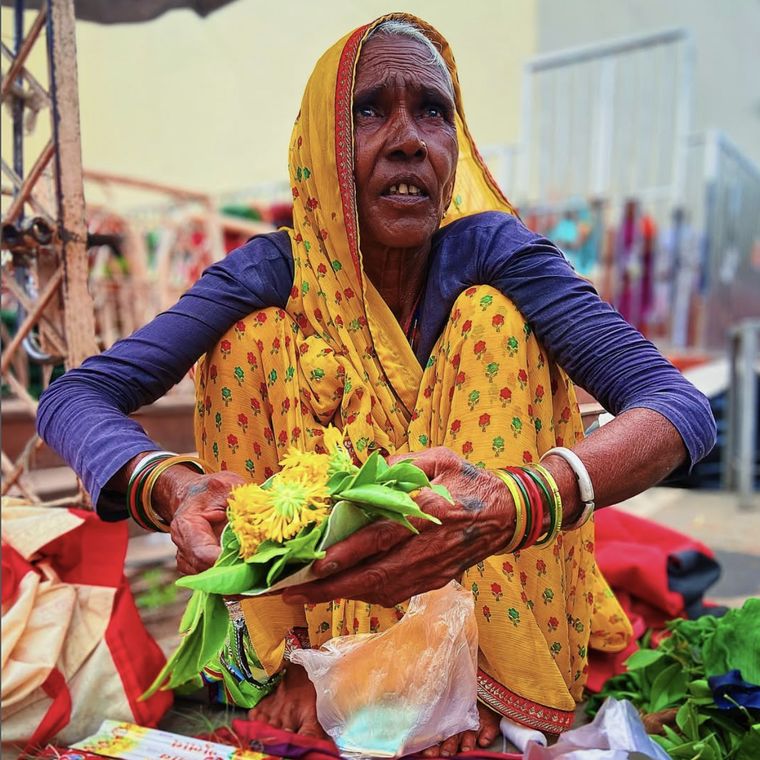 A woman selling marigold and betel leaf at a roadside stall