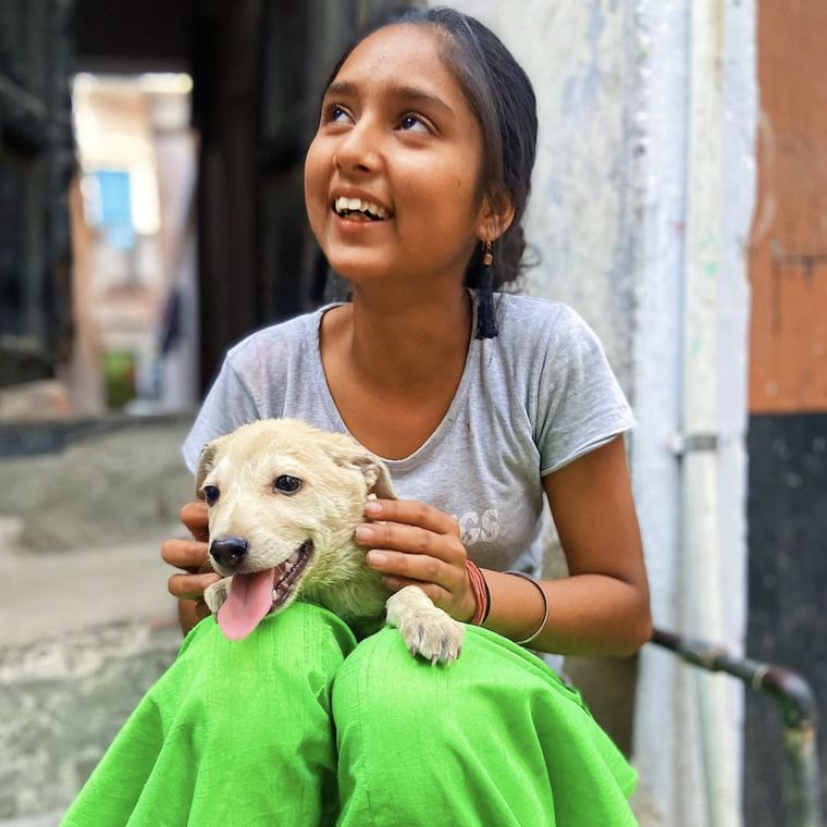 A girl holding a puppy on the steps of a neighbourhood lane