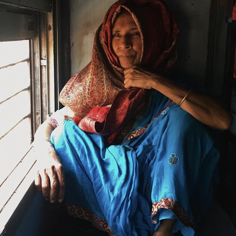 A woman seated by the window of a long-distance train coach